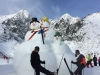 A couple of ski guests posing with the giant snowman on a day trip skiing in Tatrzanksa Lomnica, Slovakia